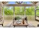 Cozy screened porch featuring a comfortable couch, wood flooring, and scenic views of the lush backyard at 669 Balmoral St, Clayton, NC 27520