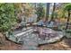 Stone patio featuring multiple seating areas, a fire pit, and a shed in a wooded backyard at 733 Hadrian Dr, Garner, NC 27529
