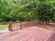 Inviting back deck with stained wood and red railings offers a serene outdoor space surrounded by trees at 81 Sallie Dr, Smithfield, NC 27577