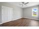 Neutral bedroom with double door closet, wood-look flooring, and a bright window at 8629 Dukes Lake Rd, Zebulon, NC 27597