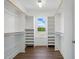 Bright walk-in closet featuring custom shelving, wooden rods, and a window providing natural light at 8629 Dukes Lake Rd, Zebulon, NC 27597
