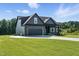 View of a craftsman style house with black trim, a two-car garage and surrounding green lawns at 8629 Dukes Lake Rd, Zebulon, NC 27597