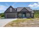 Contemporary home with a teal front door, dark gray siding, black garage door, and well-manicured lawn at 8629 Dukes Lake Rd, Zebulon, NC 27597