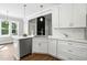 Bright kitchen featuring white cabinets, stainless steel appliances, and a view into the great room at 8629 Dukes Lake Rd, Zebulon, NC 27597