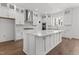 Bright kitchen features white cabinets, large island, stainless steel appliances, and hardwood floors at 9309 Field Maple Ct, Raleigh, NC 27613