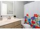 Bright bathroom features a white vanity, large mirror, and colorful shower curtain at 9404 Dawnshire Rd, Raleigh, NC 27615