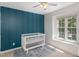Bright Bedroom features a blue accent wall, white crib, and a sunlit window at 9404 Dawnshire Rd, Raleigh, NC 27615