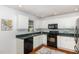 A well-lit kitchen offers white cabinets, black appliances and hardwood flooring with a decorative rug at 9404 Dawnshire Rd, Raleigh, NC 27615