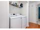 Bright laundry room features a white washer and dryer, shelving, and hardwood floors at 9404 Dawnshire Rd, Raleigh, NC 27615