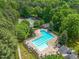 Aerial view of a community pool and tennis court surrounded by mature trees at 104 Montauk Point Pl, Cary, NC 27513