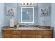 Light blue bathroom with a wood vanity with granite countertops, and a brightly lit mirror at 116 Hibiscus Dr, Clayton, NC 27527