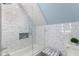 Modern bathroom featuring tiled shower-tub with glass screen beneath a slanted ceiling, adding architectural interest at 116 Hibiscus Dr, Clayton, NC 27527