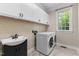 Well-lit laundry room with white cabinets and a sink, plus a large window at 116 Hibiscus Dr, Clayton, NC 27527