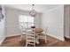 Dining area with a wooden table, four chairs, and an elegant chandelier above hardwood floors at 1230 Sunday Silence Dr, Knightdale, NC 27545