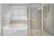 Tiled bathroom showcasing a shower with glass door, a bathtub and a window providing natural light at 1276 Dalgarven Dr, Apex, NC 27502
