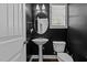 Powder room with pedestal sink, oval mirror, and modern black walls at 130 Hilldebrant Dr, Franklinton, NC 27525