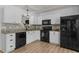 Modern kitchen featuring white cabinets, black appliances, laminate floors, and granite countertops at 14 Shire Ct, Zebulon, NC 27597