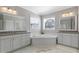 Relaxing bathroom featuring a soaking tub and two separate vanities, all complemented by natural light at 1429 Wragby Ln, Apex, NC 27502