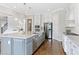 A modern kitchen featuring stainless steel appliances, a spacious island, and stylish white cabinetry at 1429 Wragby Ln, Apex, NC 27502