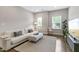 Inviting living room features hardwood floors, a light colored couch and bench, and two windows for natural light at 1429 Wragby Ln, Apex, NC 27502