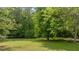Lush green backyard with large shade trees, offering a peaceful and private outdoor space at 160 Fox Run Rd, Youngsville, NC 27596