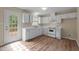 Well-lit kitchen featuring white cabinets, essential appliances, and laminate wood flooring at 160 Fox Run Rd, Youngsville, NC 27596