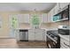 Well-lit kitchen featuring white cabinets, a stainless steel dishwasher, and an exterior door at 160 Fox Run Rd, Youngsville, NC 27596