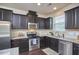 Modern kitchen with stainless steel appliances, dark cabinetry, granite countertops, and tile backsplash at 19 Sangre De Cristo Dr, Durham, NC 27705