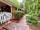 View of home's exterior with red brick pathway, green bushes, and white picket gate at 204 N Elliott Rd, Chapel Hill, NC 27514