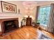 Cozy fireplace with traditional brick surround, light hardwood floors, and natural light at 204 N Elliott Rd, Chapel Hill, NC 27514