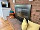 Close-up view of the brick fireplace, complemented by decorative pillows and a nearby television, adding a cozy touch at 204 N Elliott Rd, Chapel Hill, NC 27514