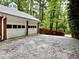 Detached two-car garage with white doors and gravel driveway set among mature trees at 204 N Elliott Rd, Chapel Hill, NC 27514