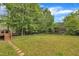 A large backyard with green grass, trees, a deck and play equipment at 206 Wagon Trail Dr, Cary, NC 27513