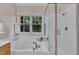 Bright bathroom with a soaking tub beneath a window and a glass enclosed shower at 206 Wagon Trail Dr, Cary, NC 27513