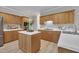 Spacious kitchen featuring light wood cabinets, stainless steel appliances, and center island with a sleek white countertop at 206 Wagon Trail Dr, Cary, NC 27513