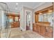 Bathroom with travertine tile, wood cabinets with vanities, and glass shower at 2117 Buckingham Rd, Raleigh, NC 27607