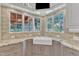 Well-lit kitchen sink area with granite countertops, travertine backsplash, and a view of the backyard at 2117 Buckingham Rd, Raleigh, NC 27607