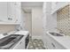 Modern laundry room featuring a front-loading washer and dryer, sink, custom cabinets, and tile floors at 2117 Buckingham Rd, Raleigh, NC 27607