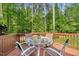 Outdoor relaxation on the back deck, featuring a table and chairs, and scenic views of the surrounding forest at 2201 Avinshire Pl, Wake Forest, NC 27587