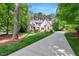 Beautiful home with long driveway, green lawn, mature trees, and colorful plantings at 2201 Avinshire Pl, Wake Forest, NC 27587