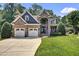 Charming brick two-story home featuring a three-car garage, manicured lawn, and lush trees at 2637 Forestbluff Dr, Fuquay Varina, NC 27526