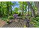 Backyard displaying a charming seating area on a wooden deck surrounded by flowers and lush greenery, ideal for relaxing outdoors at 2908 Bolo Trl, Raleigh, NC 27615