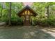 Charming cabin with gable windows, wood siding, surrounded by lush greenery, and a gravel driveway at 300 Rabbit Run, Pittsboro, NC 27312