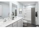 Well-lit bathroom showcasing a double vanity with framed mirrors and a shower-tub combination with a decorative shower curtain at 302 N Coral Bells Way, Four Oaks, NC 27524