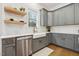 Spacious kitchen with quartz countertops, farmhouse sink, gray cabinetry, and stainless steel dishwasher at 304 Channel Cove Dr, Holly Springs, NC 27540