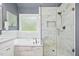 Bright bathroom featuring a soaking tub, glass shower enclosure, and marble tile design at 308 Hassellwood Dr, Cary, NC 27518