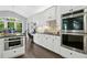 Well-lit kitchen featuring stainless appliances, granite counters, white cabinetry, and a breakfast nook with wooded views at 308 Hassellwood Dr, Cary, NC 27518