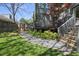 Beautiful backyard with a well-manicured lawn, stone walkway, and flowering plants near a gray two-story home at 310 Georgetown Rd, Raleigh, NC 27608