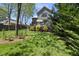 Lush backyard with a well-maintained lawn, ornamental shrubs, and a patio area of a gray two-story house at 310 Georgetown Rd, Raleigh, NC 27608