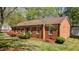 Side angle of all-brick home with manicured lawn, mature trees, and flowering bushes at 3126 Truitt Dr, Burlington, NC 27215